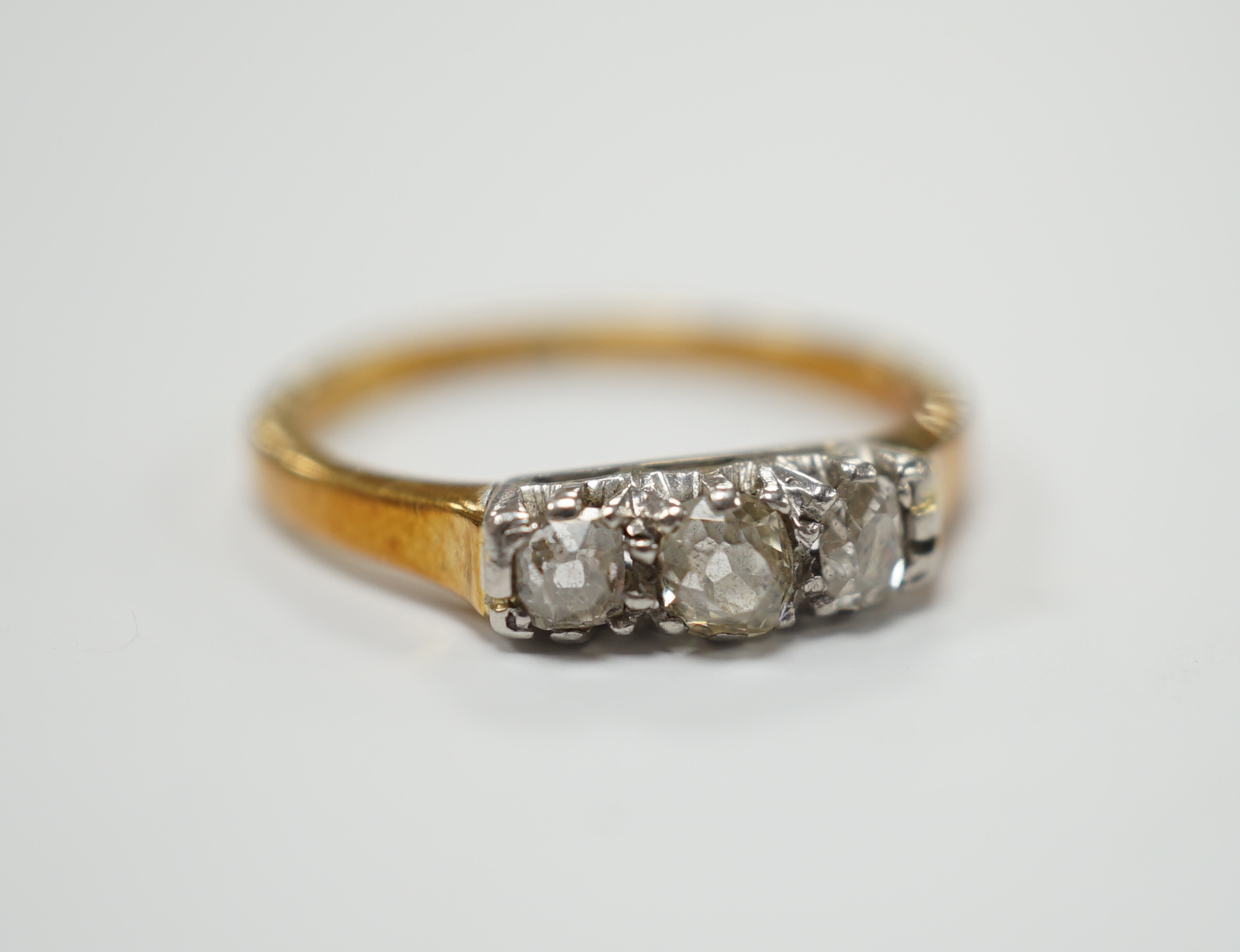 An 18ct, plat. and three stone diamond set ring, size K/L, gross weight 2.5 grams.